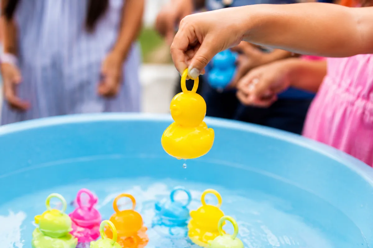 Gros plan sur les mains d'un enfant déballant un paquet cadeau coloré entouré de confettis